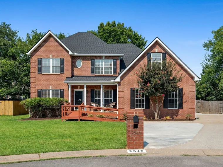 Two-story red brick home with black shutters, a covered front porch and a crape myrtle on a cul-de-sac at 2547 Patricia Circle, Murfreesboro, Tennessee