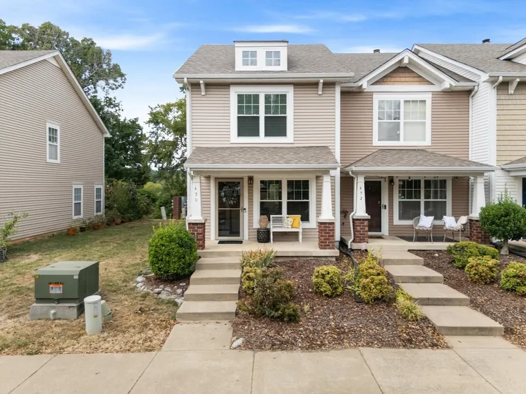 End-unit townhome with tan siding, a covered front porch and brick column bases at 450 Flintlock Court, Nashville, Tennessee